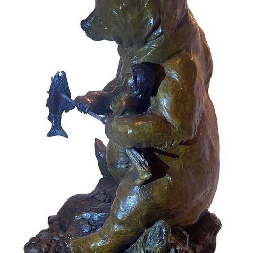 This bronze bear sculpture brings a sense of humor, complexity, and even humility to the theme of Ransom. Created by Walt Horton it features a large bear in an upright, almost human-like stance, holding a young boy in one paw and a fish has been speared by the young boy fish in the other. The scene is whimsical, suggesting that the bear is either demanding a trade for the fish or holding the fish as leverage in a humorous negotiation.